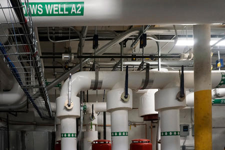 vertical and horizontal pipes in the basement marked with green identification labels