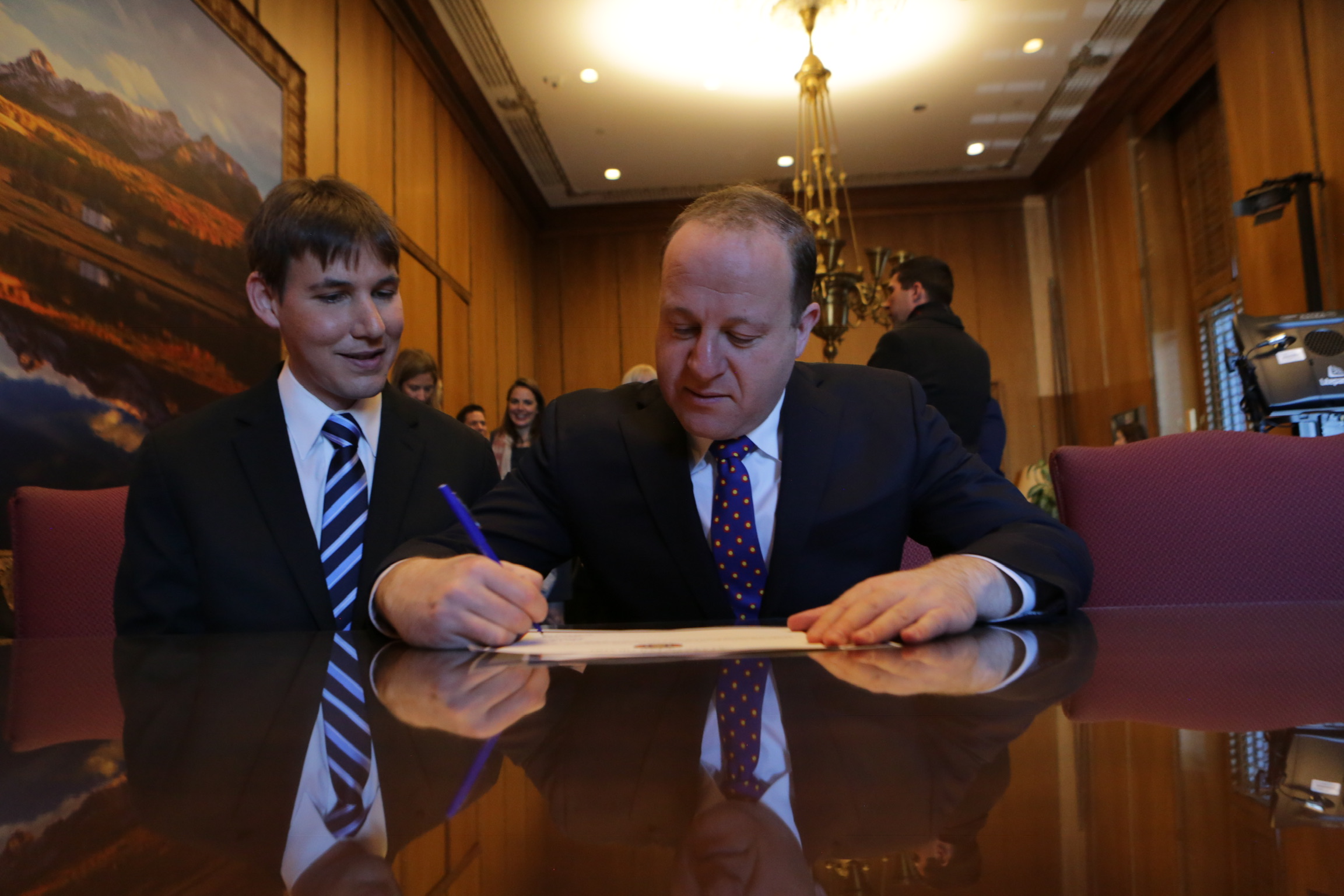 Governor Polis with First Gentleman Reis Signing a Document