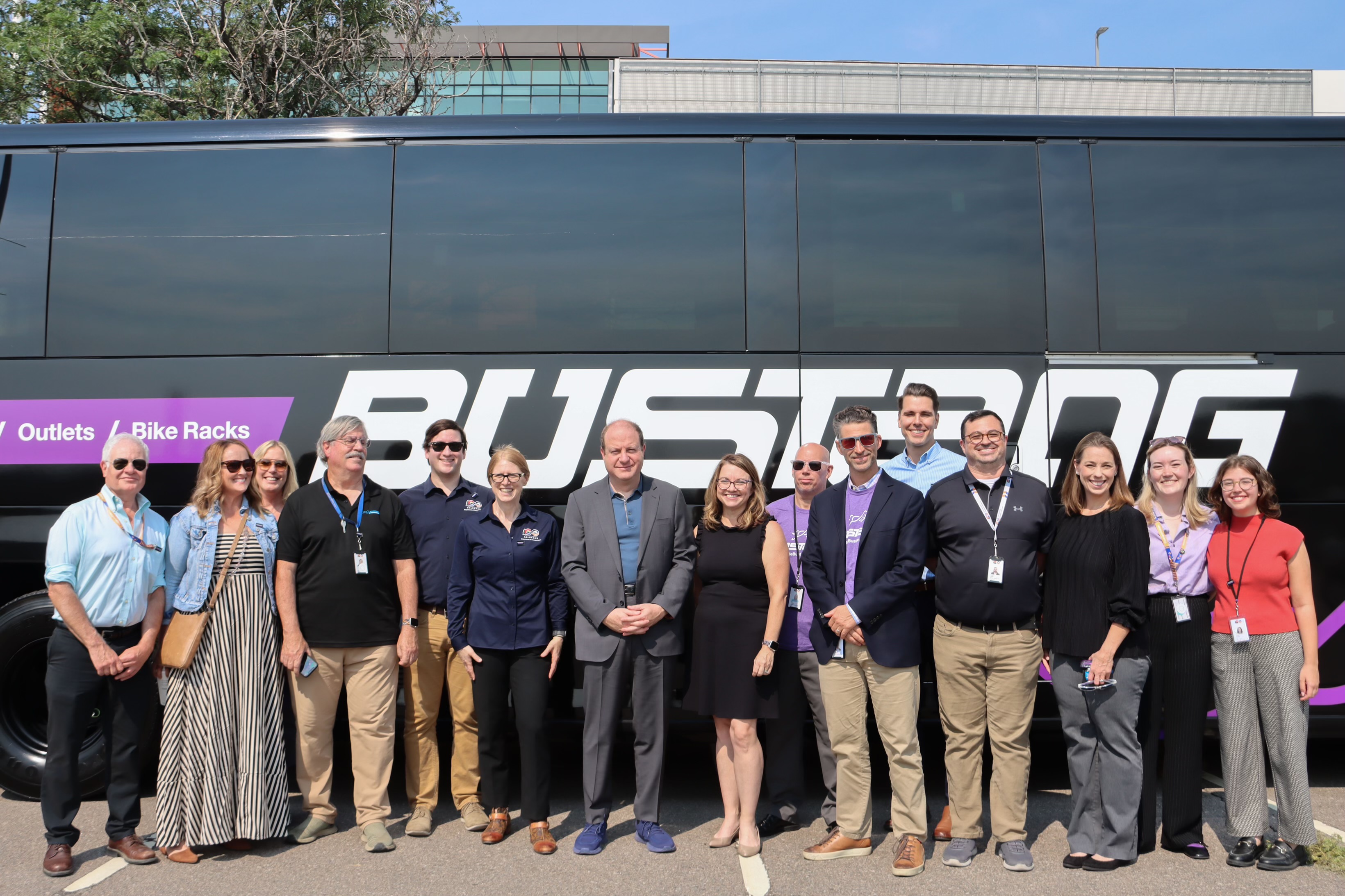 Governor Polis and group of transportation workers stand in front of bustang bus
