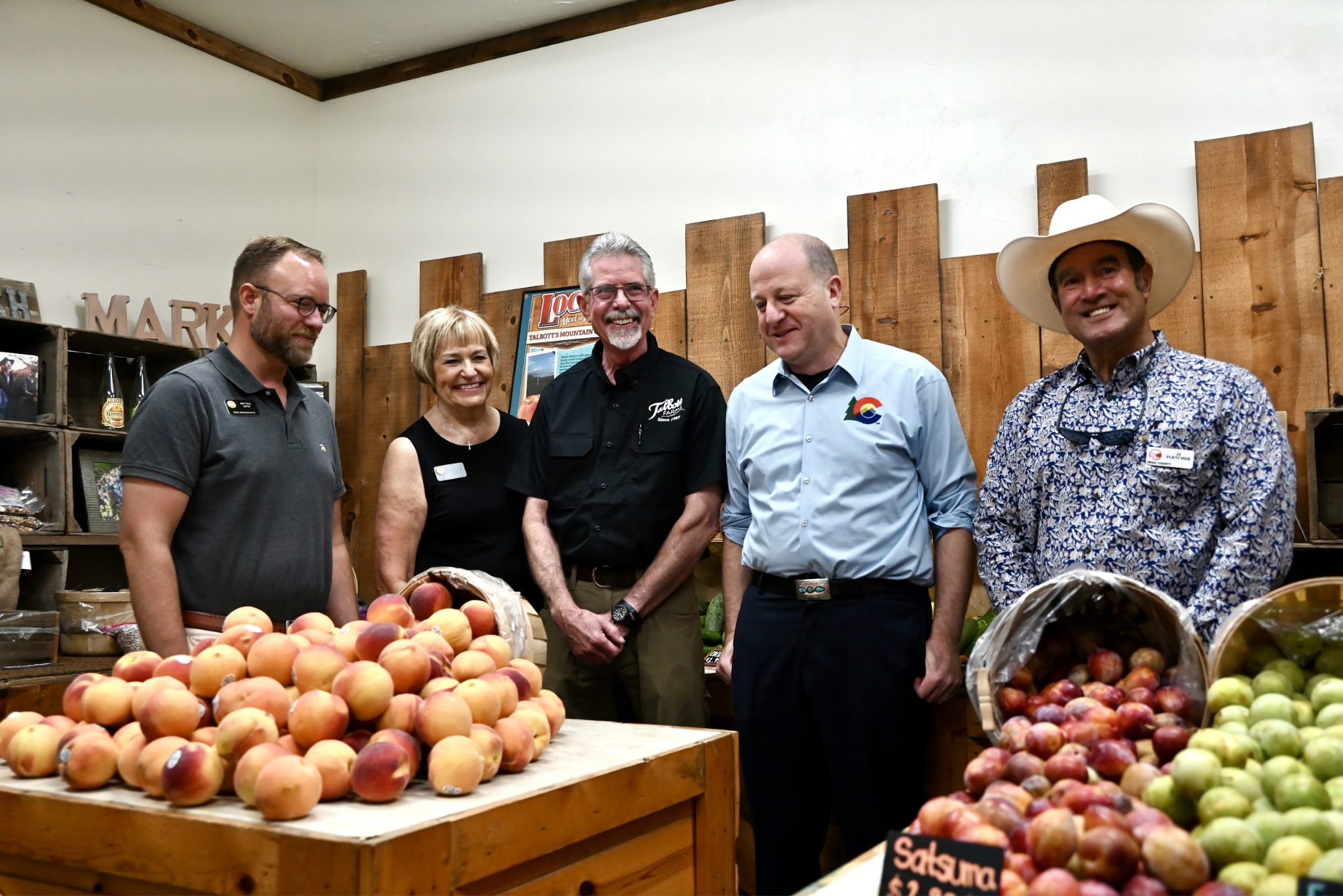 Governor Polis at peach stand with members of the State Legislature and county commisioners 