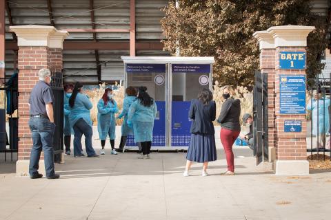 Health care workers and others wearing masks in front of testing kiosks.